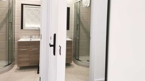 Un baño moderno con cabina de ducha de vidrio, tocador con espejo y un inodoro.