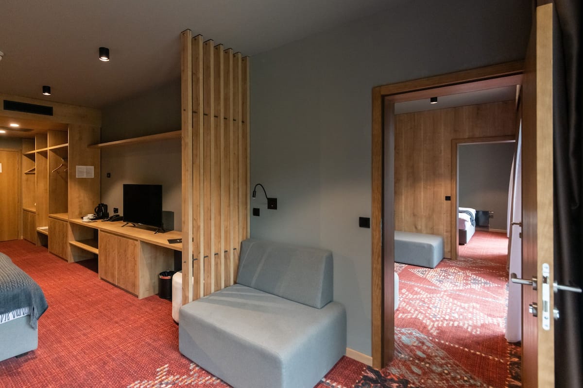 Een moderne hotelkamer met een bed, een bureau met een computer, een televisie en een groot raam.
