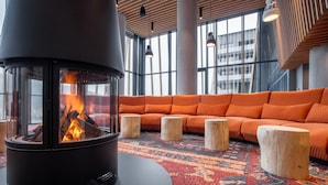 A modern interior with a wood-burning stove, orange seating, and large windows.
