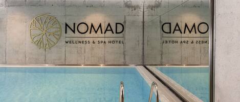 A swimming pool area with a NOMAD WELLNESS & SPA HOTEL sign.