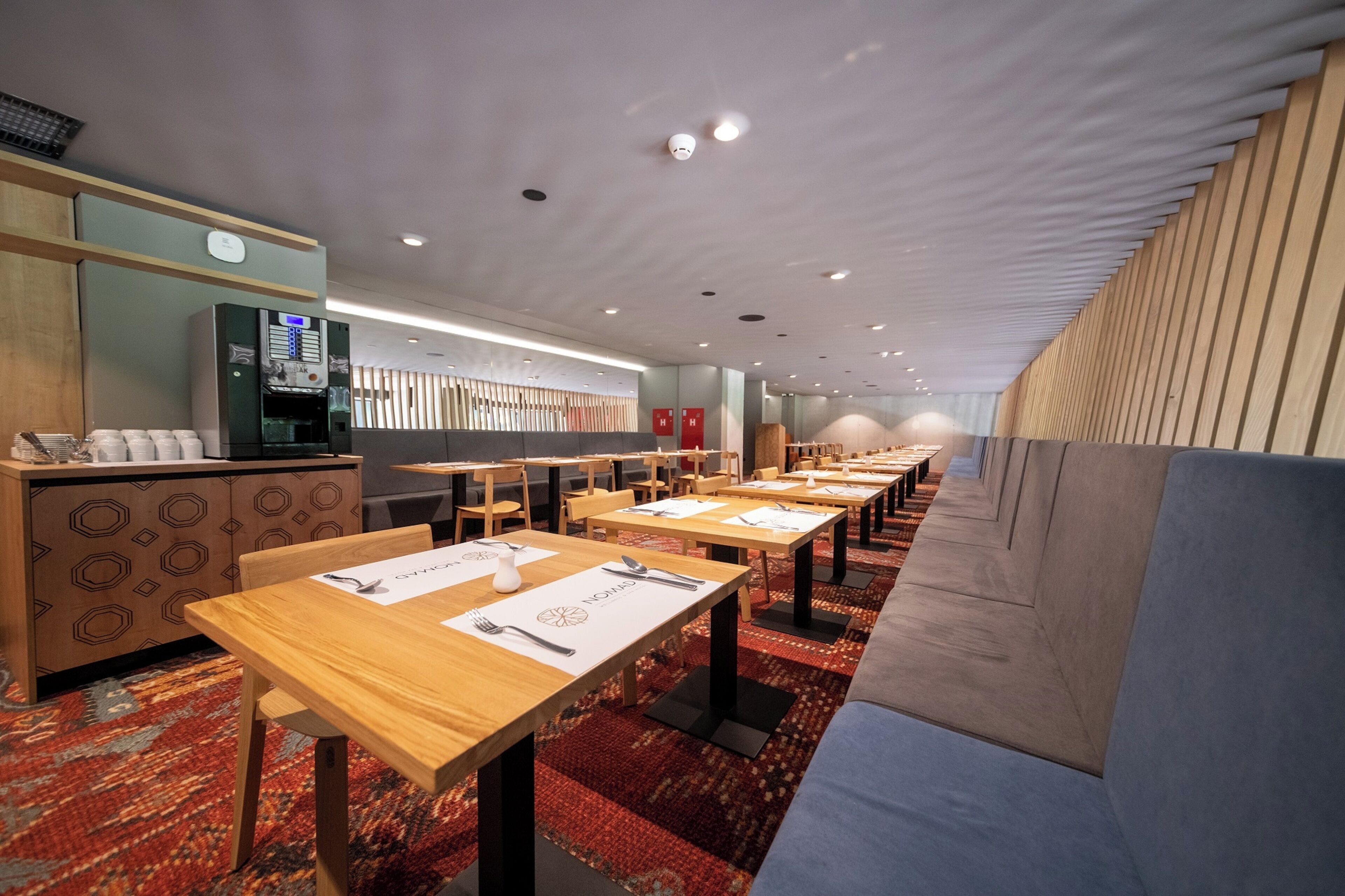 Un'area ristorazione moderna con tavoli e sedie in legno e un banco buffet.