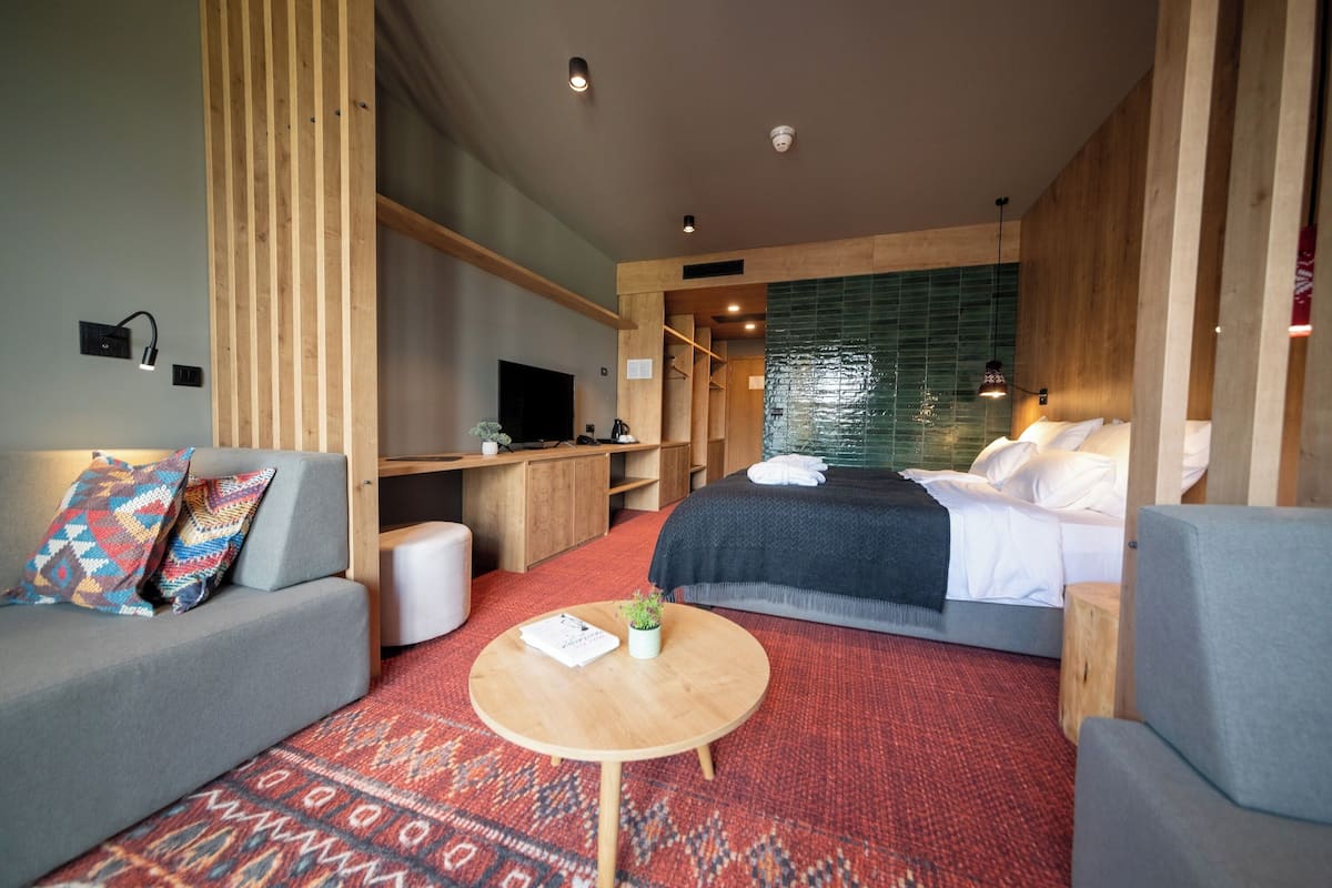 Een moderne hotelkamer met een bed, een bank, een tafeltje en een televisie.