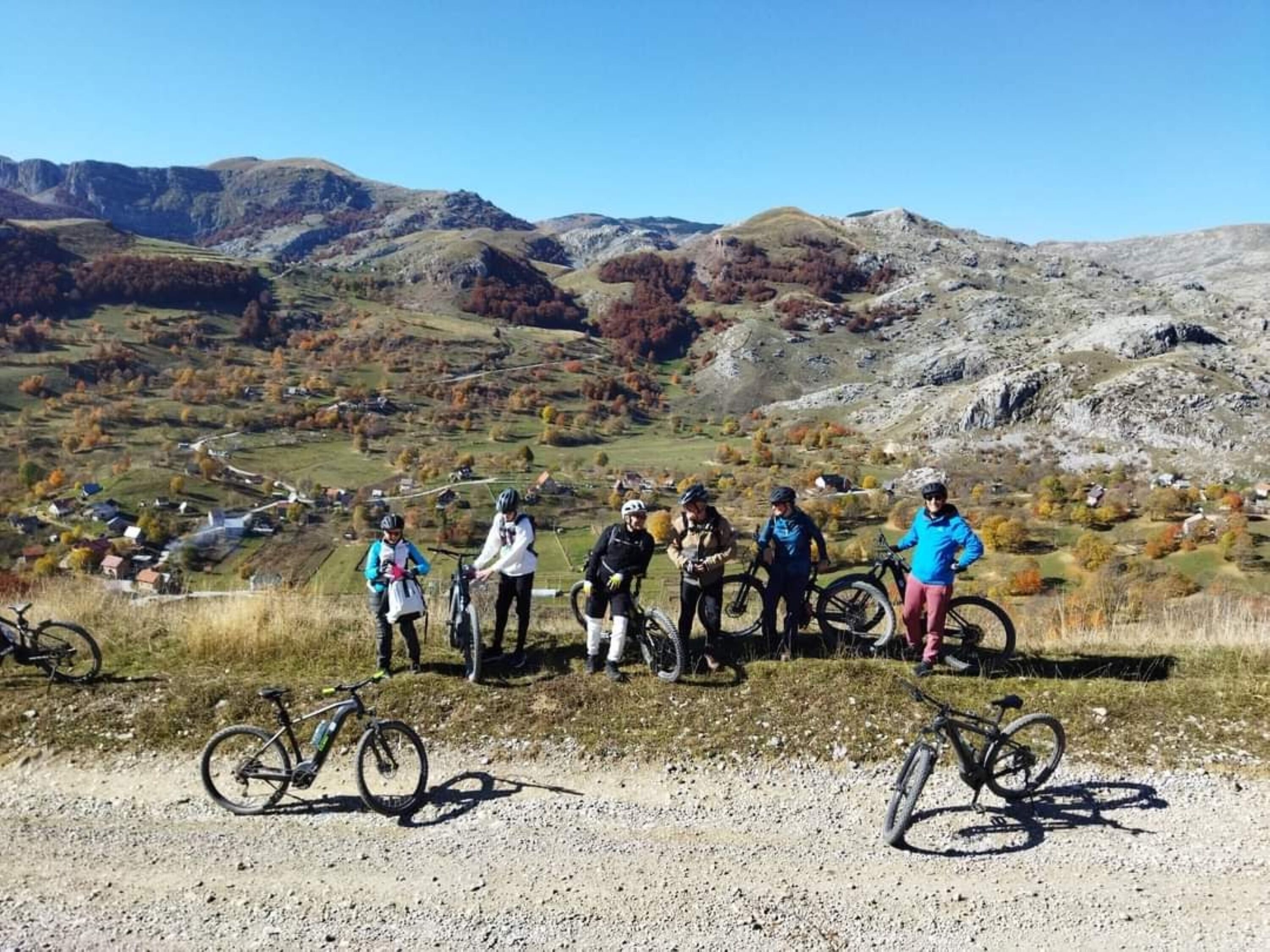 A group of cyclists on a gravel path with a mountainous landscape in the background.