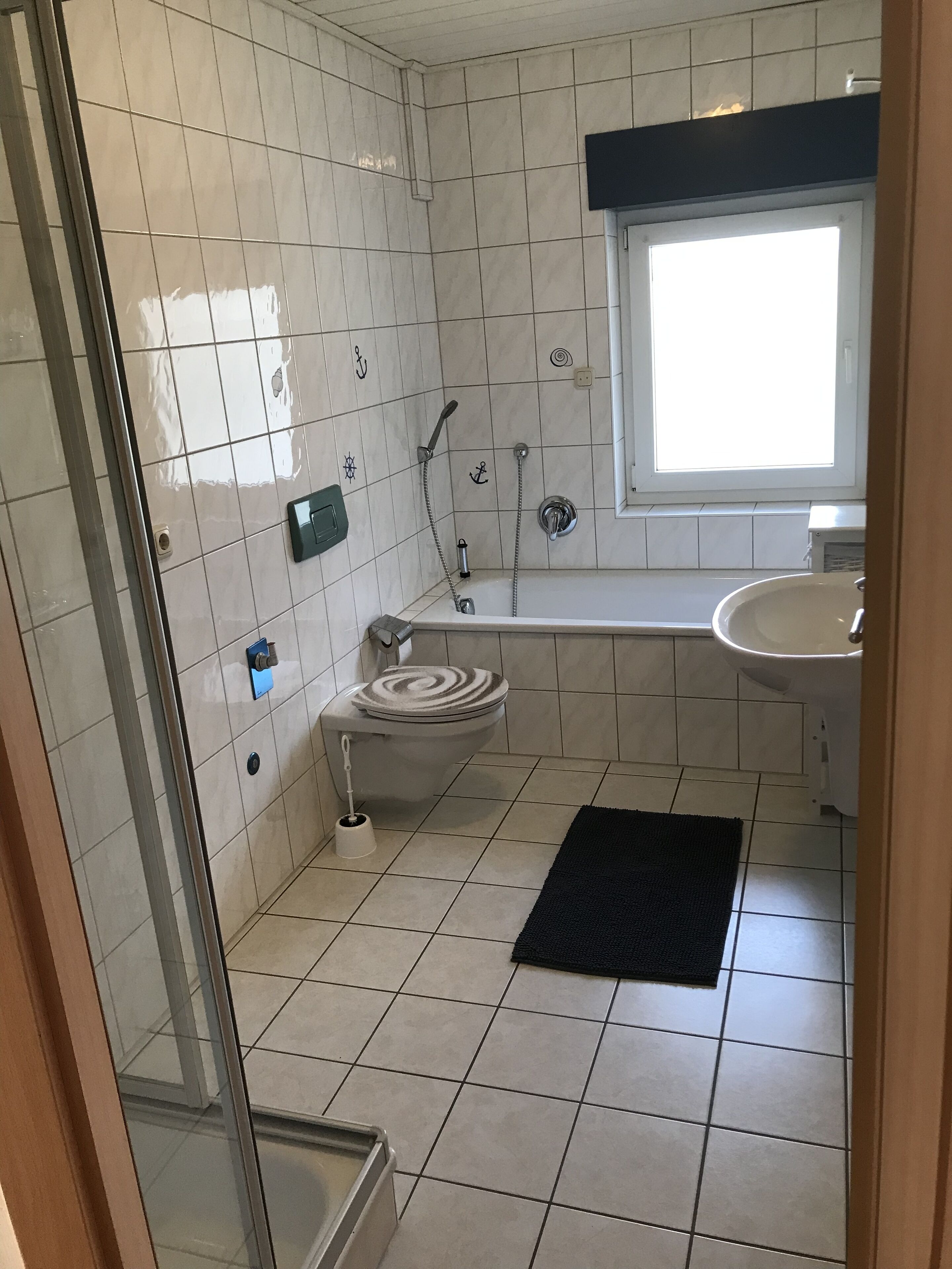 A bathroom with a toilet, shower, and sink.