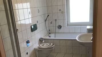 Et badeværelse med toilet, brusebad og vask.