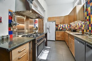 A modern kitchen with stainless steel appliances, wooden cabinets, and a colorful tile backsplash.