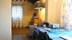 Un comedor con una mesa preparada para dos, una lámpara y una silla con funda estampada.
