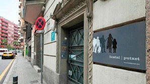 Un edificio con un letrero que dice 'hostal putxet' y una señalización de estacionamiento con la letra 'P'.