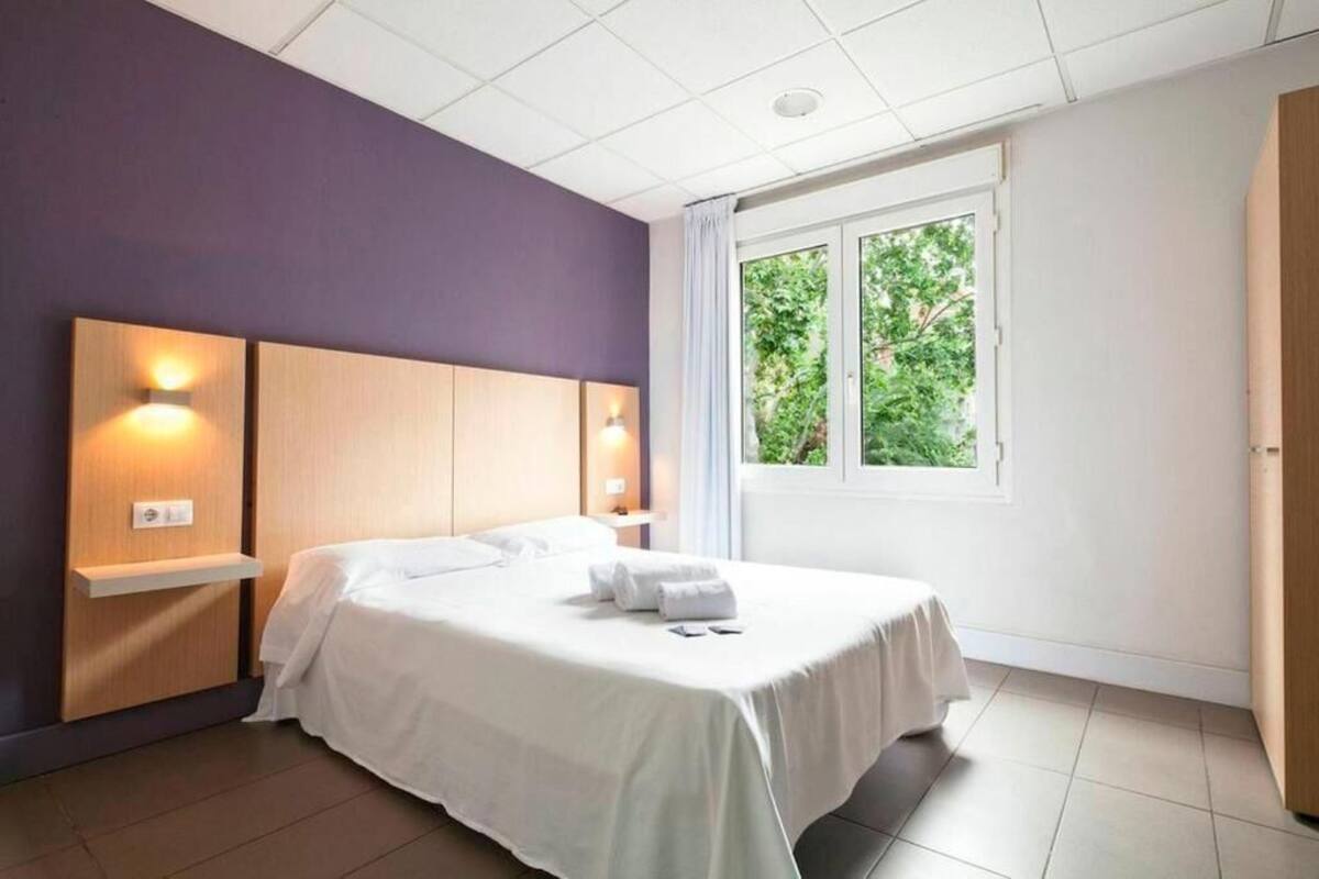 Habitación de hotel moderna con una cama grande, mesitas de noche empotradas y una ventana con vistas a zonas verdes.
