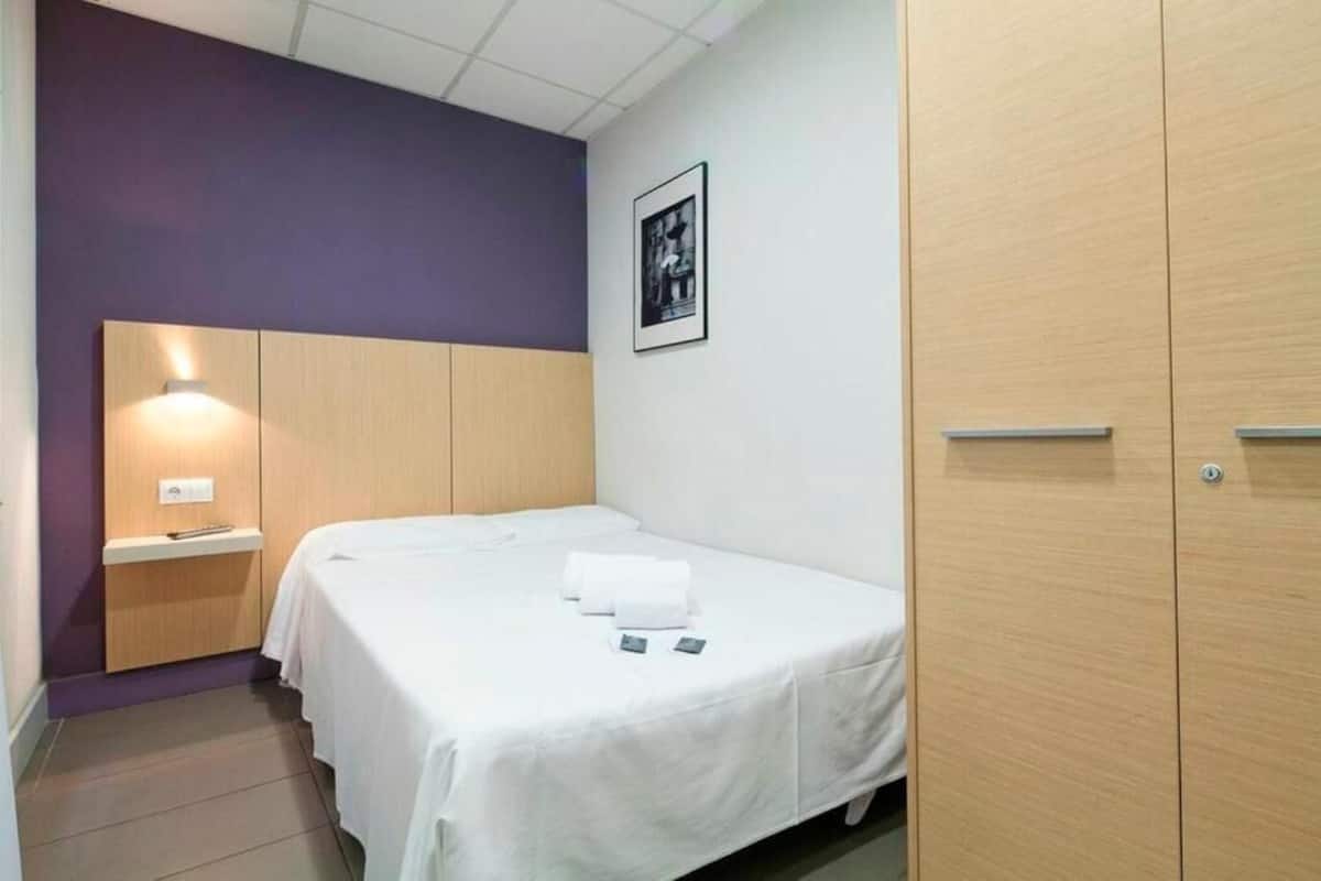 Un dormitorio pequeño y ordenado con una cama individual, una mesita de noche y un armario.