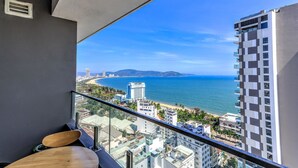 Un balcon avec vue sur l’océan et sur le paysage urbain.