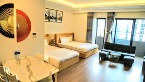 Une chambre d’hôtel avec deux lits, un canapé, une table à manger avec des chaises et des œuvres d’art aux murs.