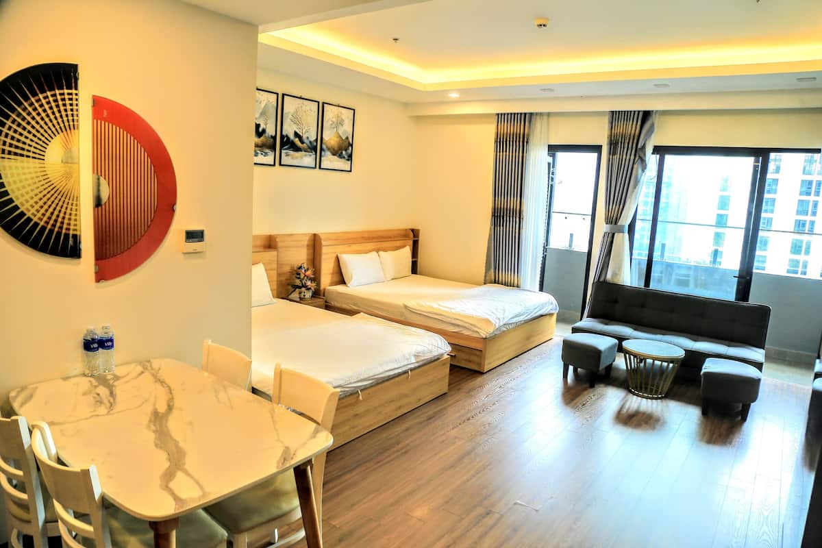 A hotel room with two beds, a sofa, a dining table, and a large window.