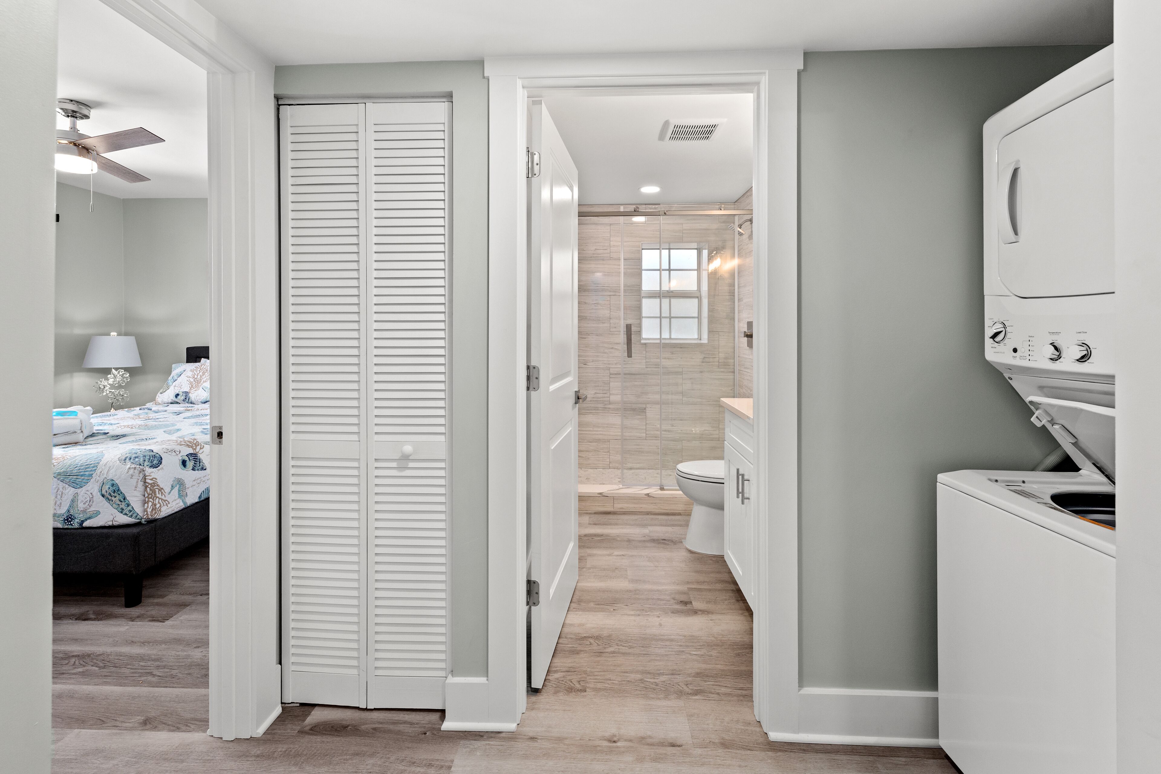 Une salle de bain moderne équipée d’une douche, de toilettes et d’un lave-linge blanc.