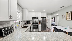 Una cocina moderna con armarios blancos, electrodomésticos de acero inoxidable y una encimera de granito.