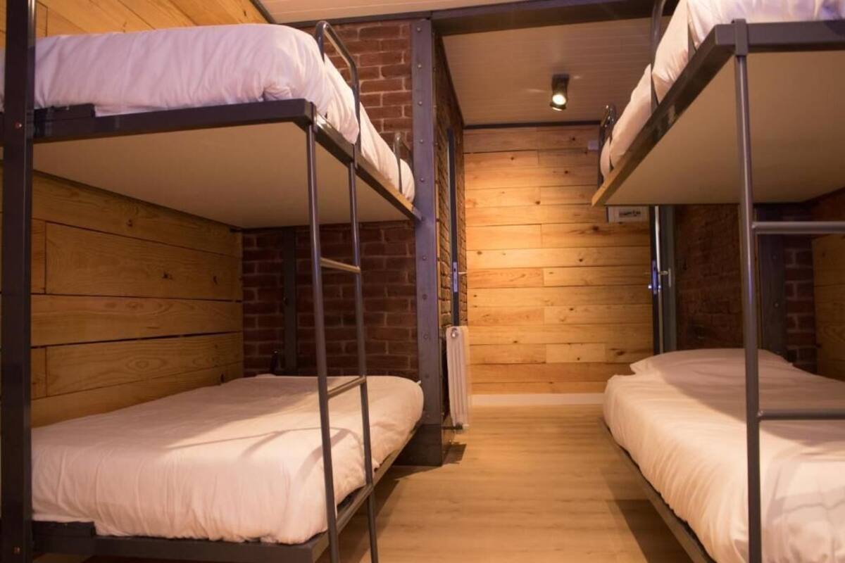 Une chambre avec des lits superposés, des murs en bois et un mur d’accent en briques.