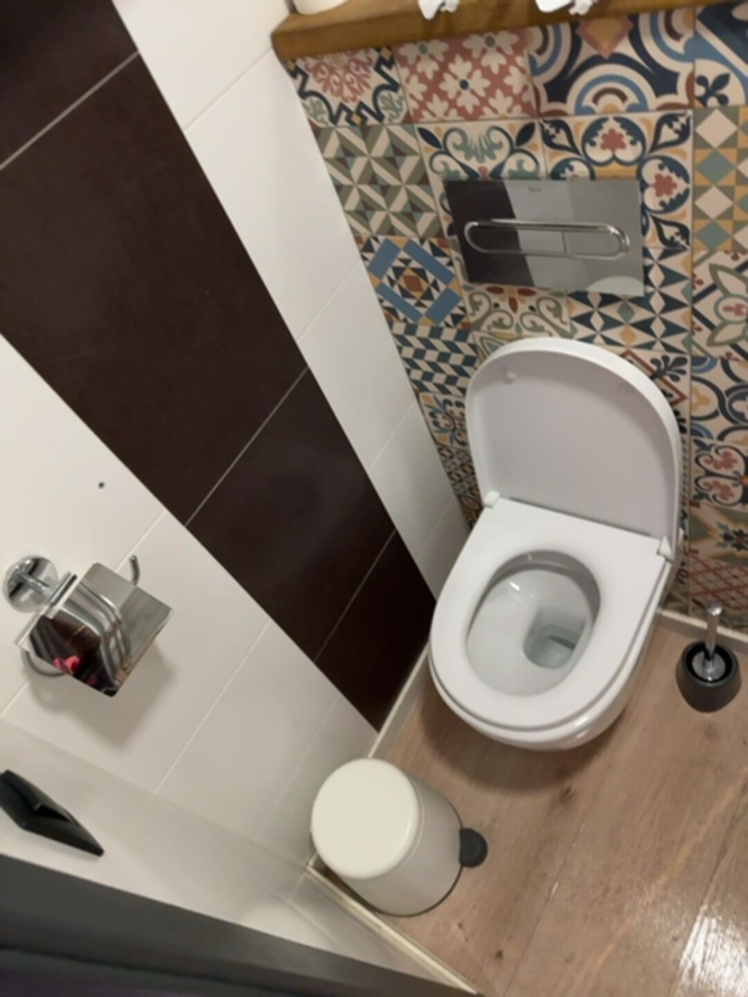 Une salle de bain équipée de toilettes, d’une poubelle et d’un porte-rouleau de papier toilette.