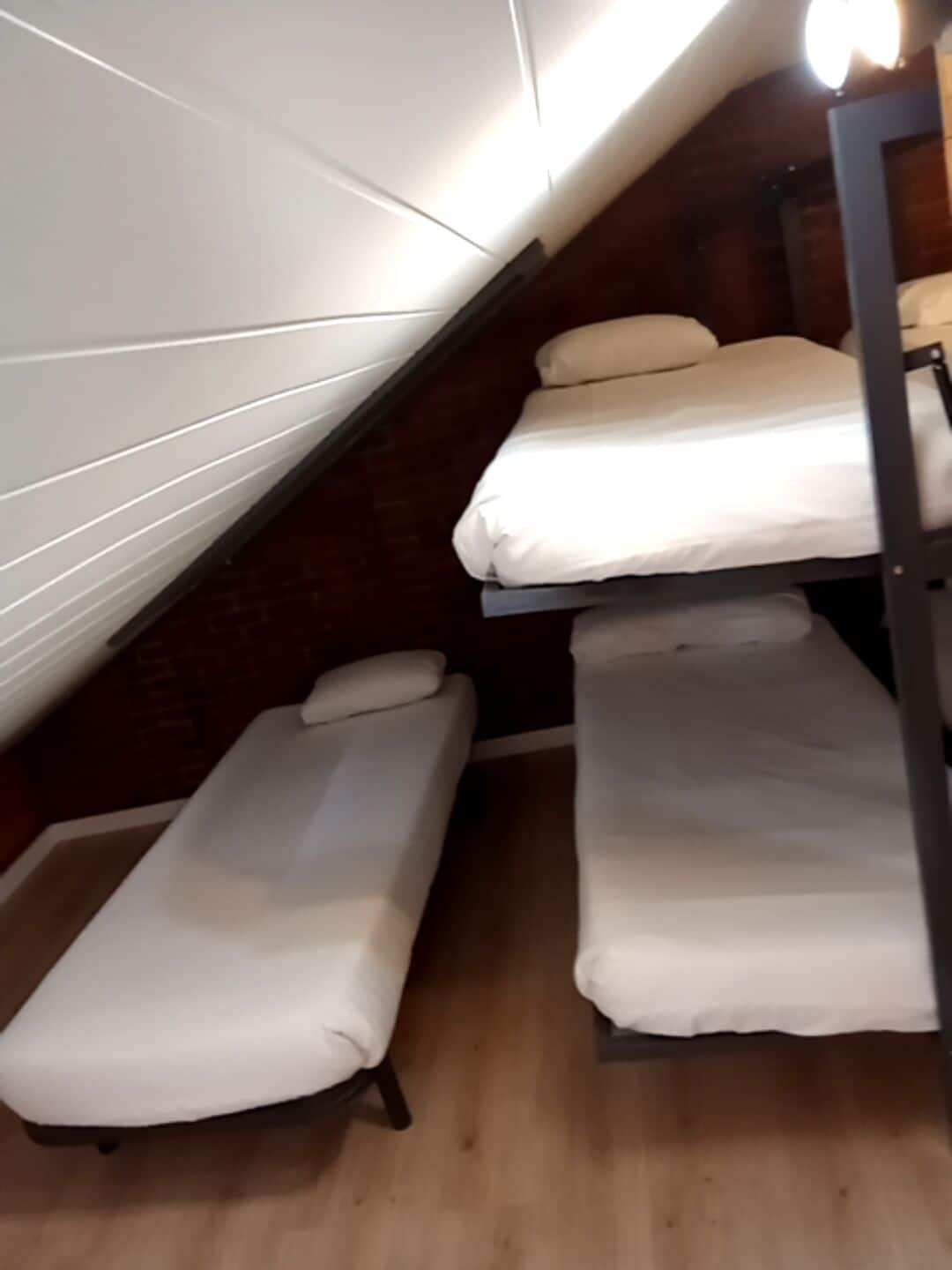 Habitación tipo dormitorio con literas y techo inclinado.