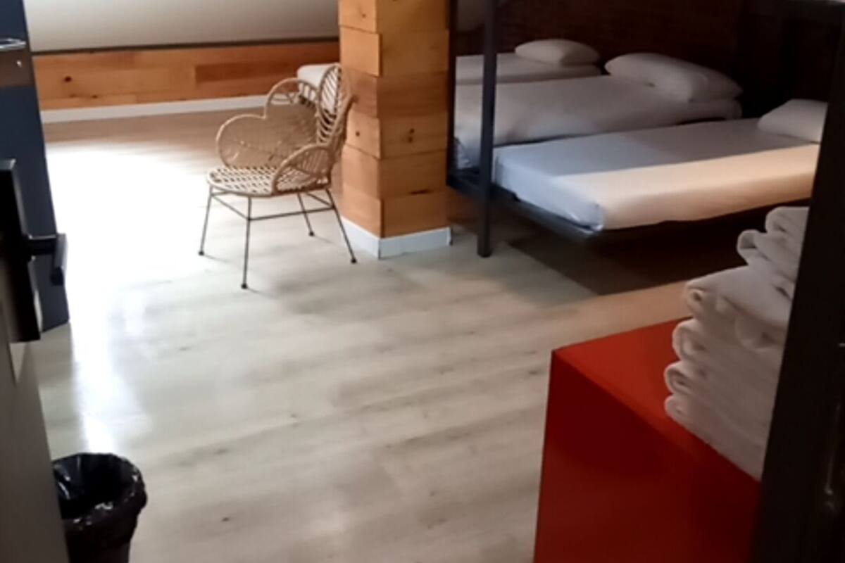 Une chambre de dortoir avec des lits superposés, une chaise en bois et un meuble de rangement rouge.