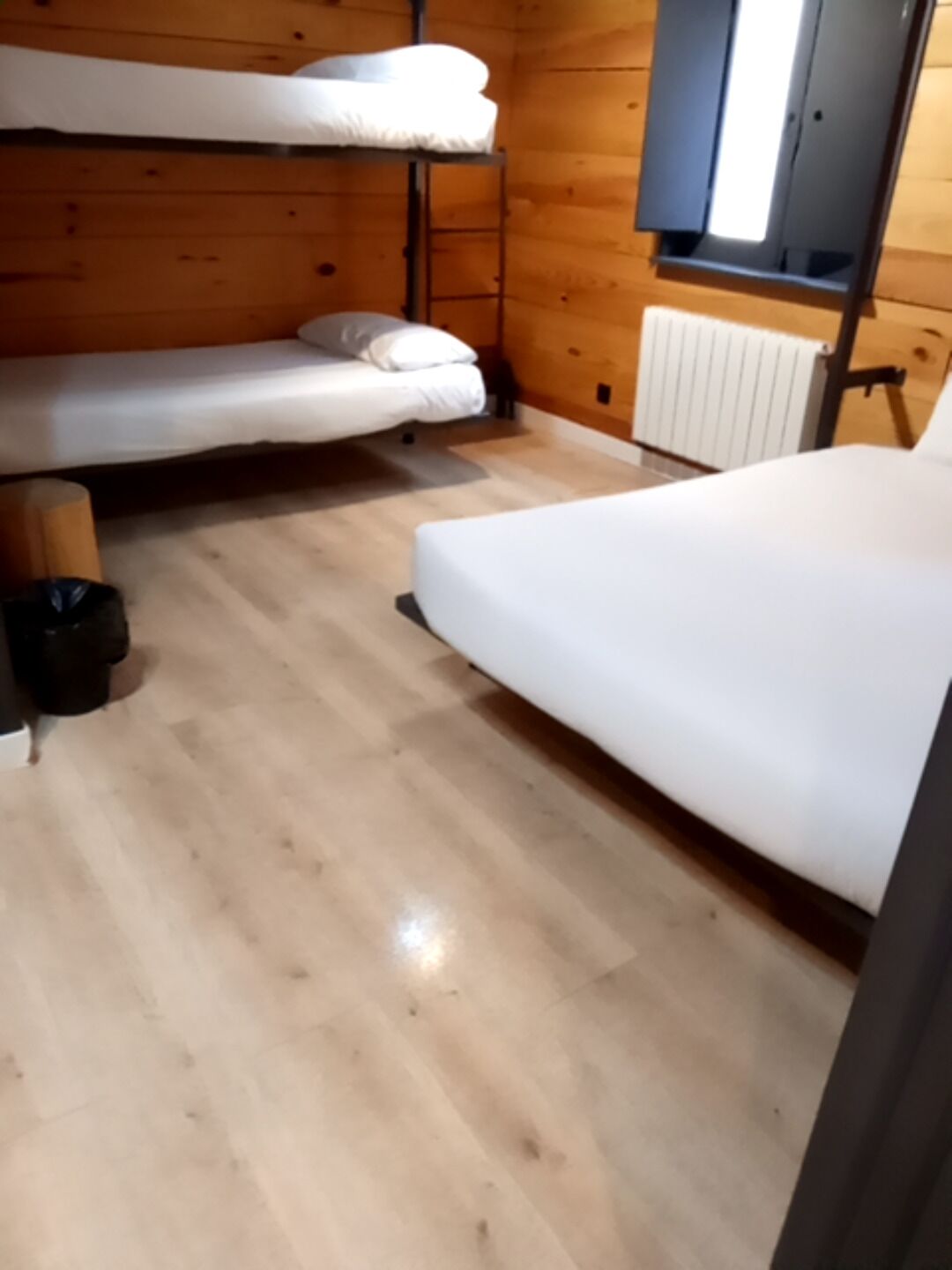 Interior de cabana com beliche, cama de solteiro e radiador.
