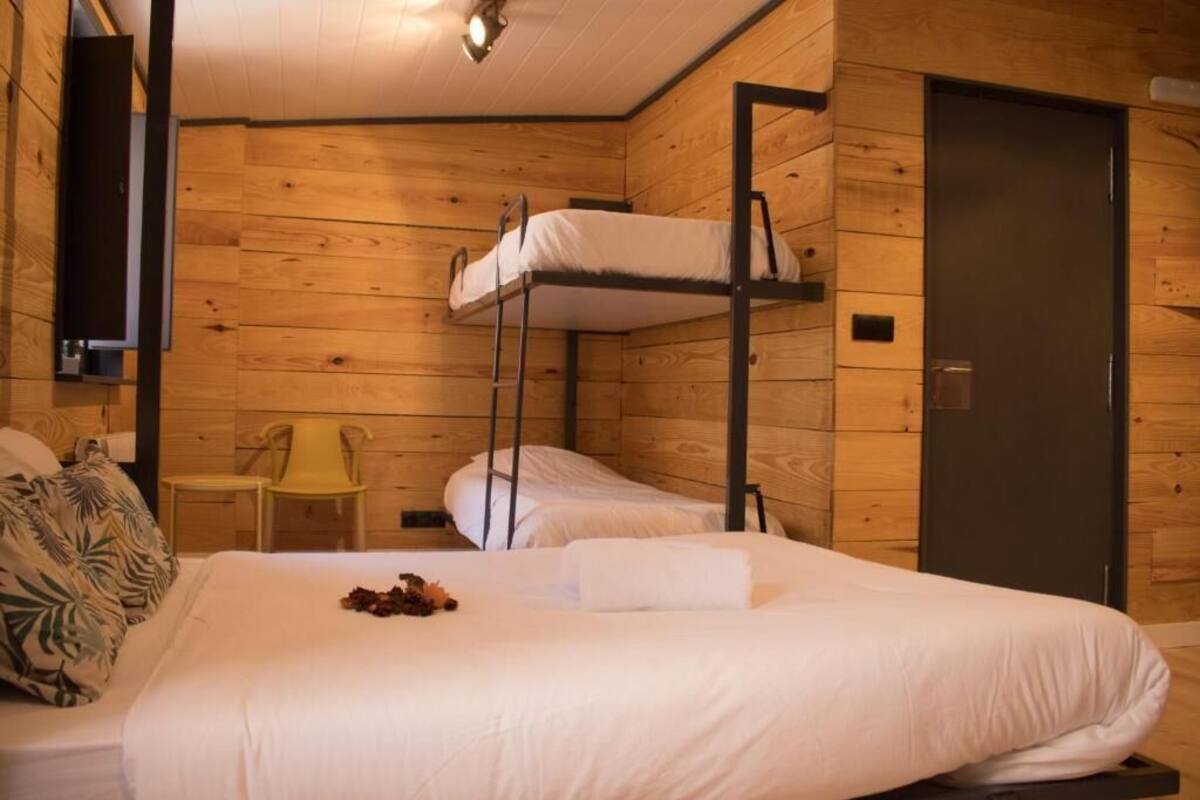 Une pièce avec des lits superposés, une petite table, une chaise et une porte.