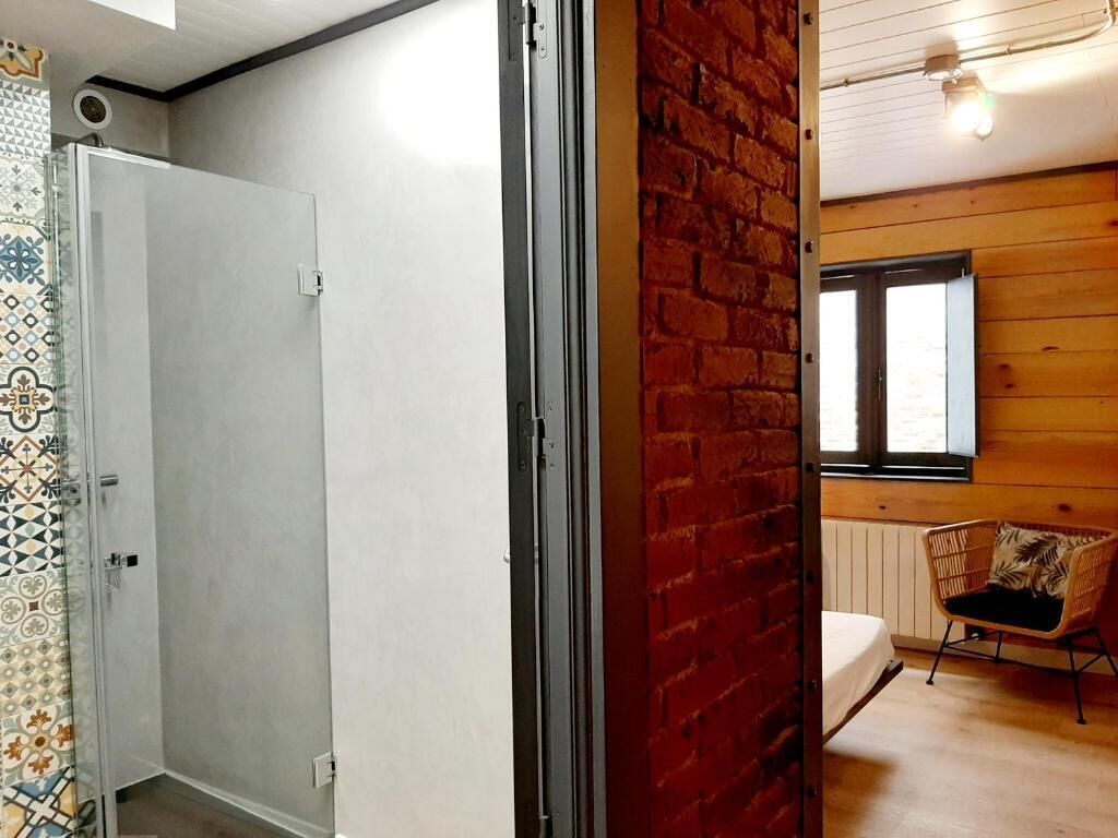 Una habitación con una puerta blanca, una pared de ladrillo, una ventana y una silla de mimbre.