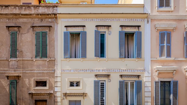 Une rangée de bâtiments dotés de nombreuses fenêtres et portes, dont certaines sont pourvues de volets.