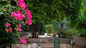 Un jardin agrémenté de fleurs roses, d’escaliers en pierre et de lampes sphériques.
