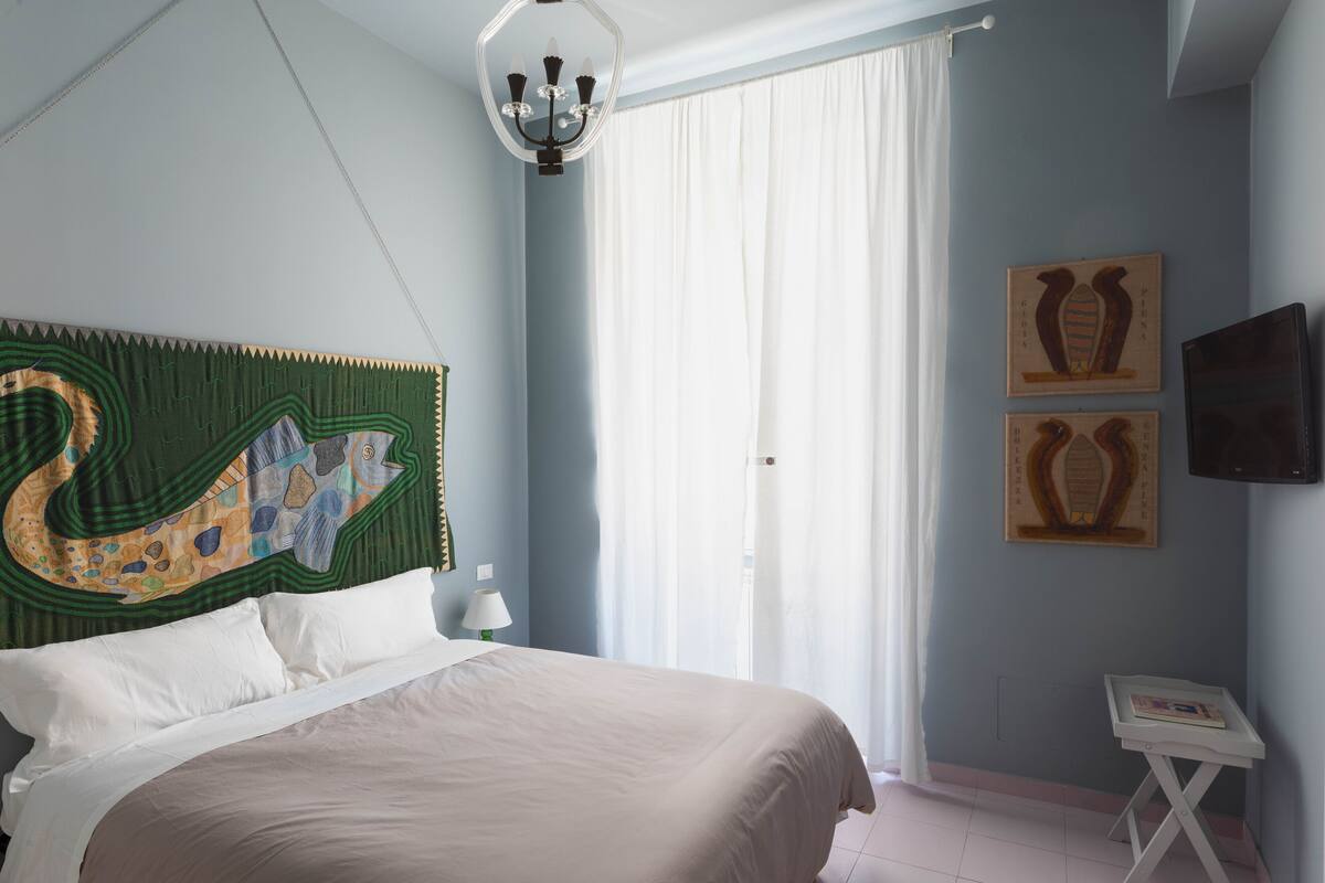 A bedroom with a bed, a nightstand, a lamp, and a wall-mounted TV.