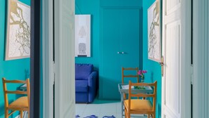 Une pièce aux murs de couleur turquoise, avec un canapé bleu et une table en bois entourée de chaises.