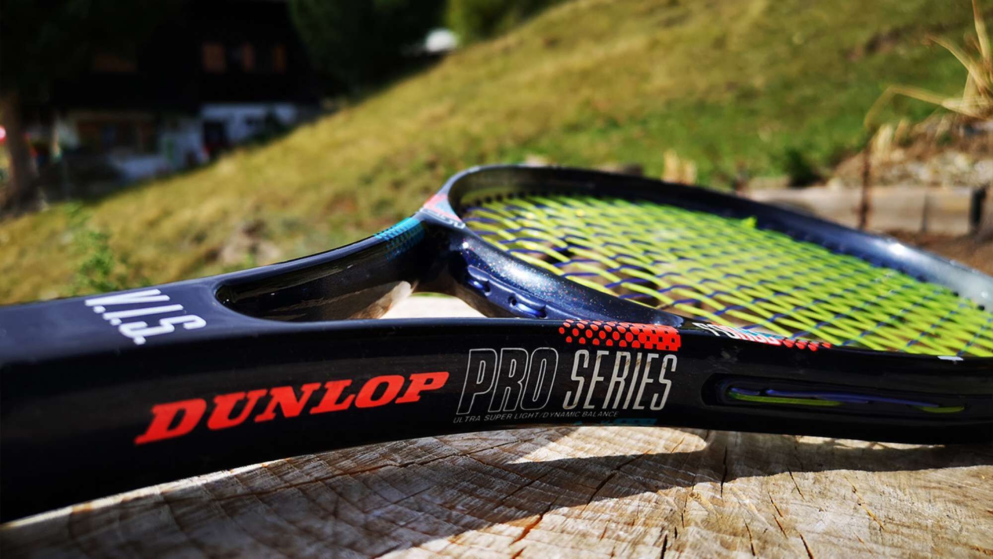 Ein Tennisschläger mit 'DUNLOP PRO SERIES'-Branding auf einer Holzoberfläche.