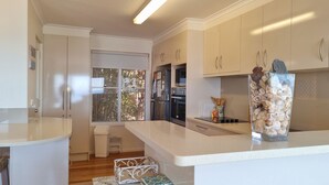 Una cucina moderna con mobili bianchi, forno integrato e un'ampia finestra.