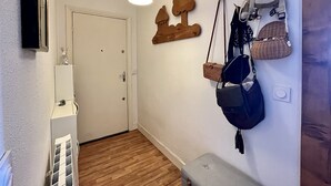 A hallway with a wooden floor, a white door, a hanging lamp, and wall-mounted bags. - Calm sea view family appartment in historical town center (Villers-sur-Mer)