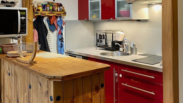 A kitchen with wooden beams, red cabinets, a wooden island, and a microwave. - Calm sea view family appartment in historical town center (Villers-sur-Mer)
