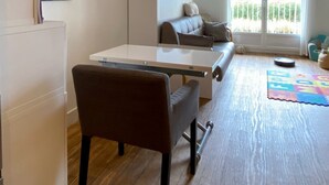 A modern living room with a sofa, a dining table, and a kitchen area with a refrigerator. - Calm sea view family appartment in historical town center (Villers-sur-Mer)