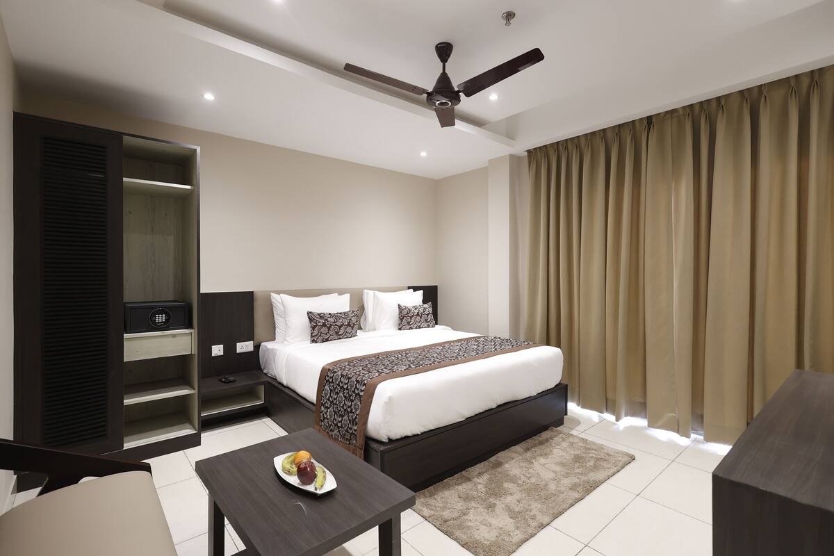Une chambre d’hôtel moderne équipée d’un grand lit, d’un bureau, d’une armoire et d’un ventilateur de plafond.