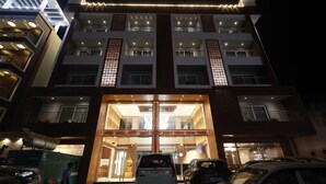A multi-story hotel with a central entrance, large windows, and a parking area in front. - Pride Biznotel Canopus Digha (Kanthi)