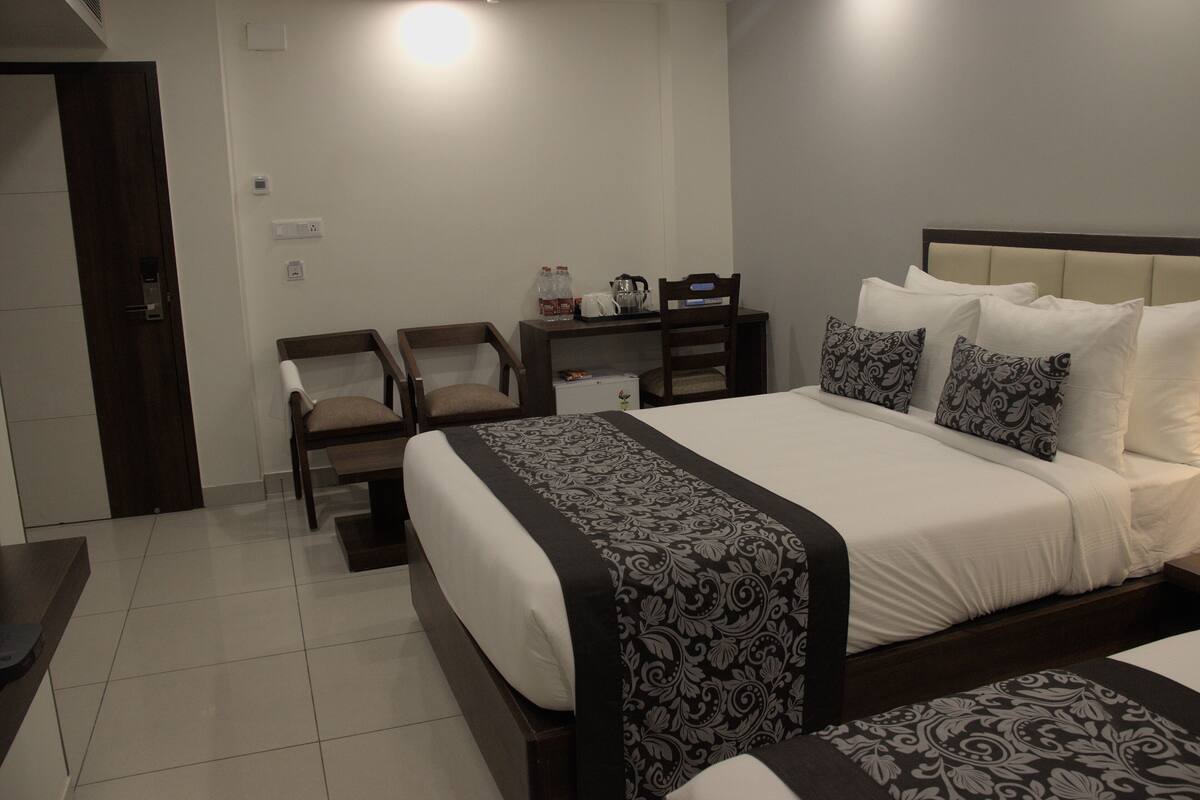 Une chambre d’hôtel avec un grand lit, un bureau, deux chaises et une petite table.
