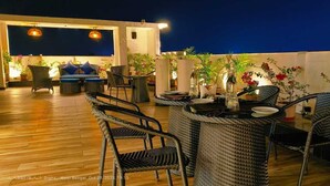 An outdoor dining area with wicker furniture and potted plants. - Pride Biznotel Canopus Digha (Kanthi)