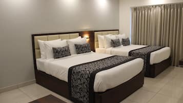 Cama doble con cabecera oscura y ropa de cama blanca, mesita de noche y ventana con cortinas.