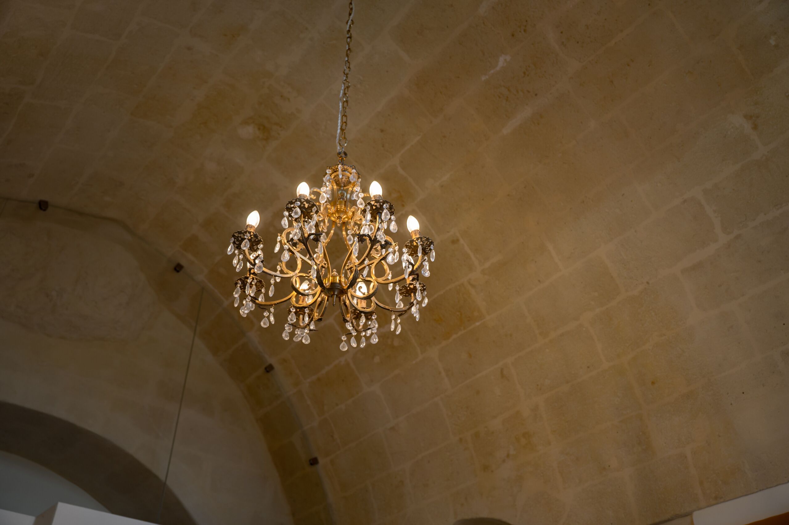 Un lustre à plusieurs bras, orné de décorations en cristal, suspendu au plafond.