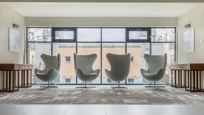 A spacious room with large windows, three modern chairs, and a patterned floor.