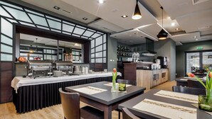 A modern restaurant with a bar area, wooden flooring, and a view through large windows.