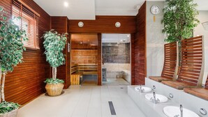 A modern bathroom with wooden walls, a glass shower enclosure, and multiple sinks.