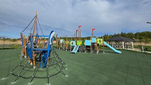 A playground with various play structures, including a climbing frame and slides, set on a green surface. - Spacious Apartment | Balcony, Parking, 400 m to the Beach (Grzybowo)