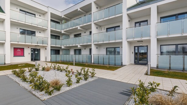 A modern multi-story building with balconies, a landscaped courtyard, and a clear view of the sky. - Spacious Apartment | Balcony, Parking, 400 m to the Beach (Grzybowo)
