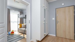 A room with a bunk bed, a white wardrobe, a wooden door, and a small rug. - Spacious Apartment | Balcony, Parking, 400 m to the Beach (Grzybowo)