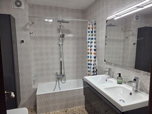 A bathroom with patterned tiles, a shower, a bathtub, a sink, and a mirror.