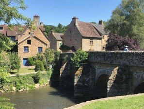 A stone bridge over a river with traditional stone buildings on either side. - "Les Nichoirs" Cozy cottage in Ussy in the Normandy countryside (Ussy)