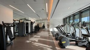 Academia moderna com equipamentos de cardio, estações de musculação e espelhos nas paredes.